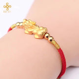 Red string bracelet with gold plated Pixiu charm, a symbolic accessory for attracting wealth and prosperity.