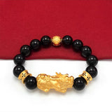 Gold-plated Pixiu charm on a black beaded bracelet, a feng shui accessory for men to attract wealth flow