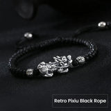 Men's beaded bracelet with silver Pixiu charm on black string, a symbolic feng shui piece for wealth manifestation