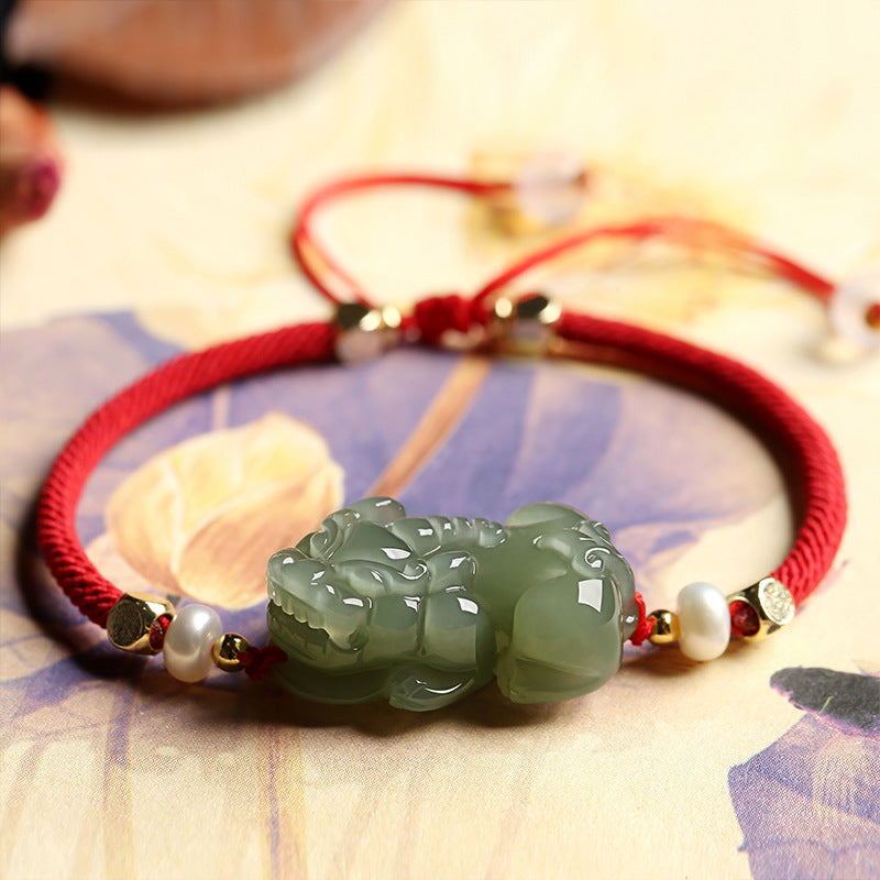 Green jade beaded bracelet with Pixiu charm and red string, a symbolic accessory for wealth manifestation and abundance.