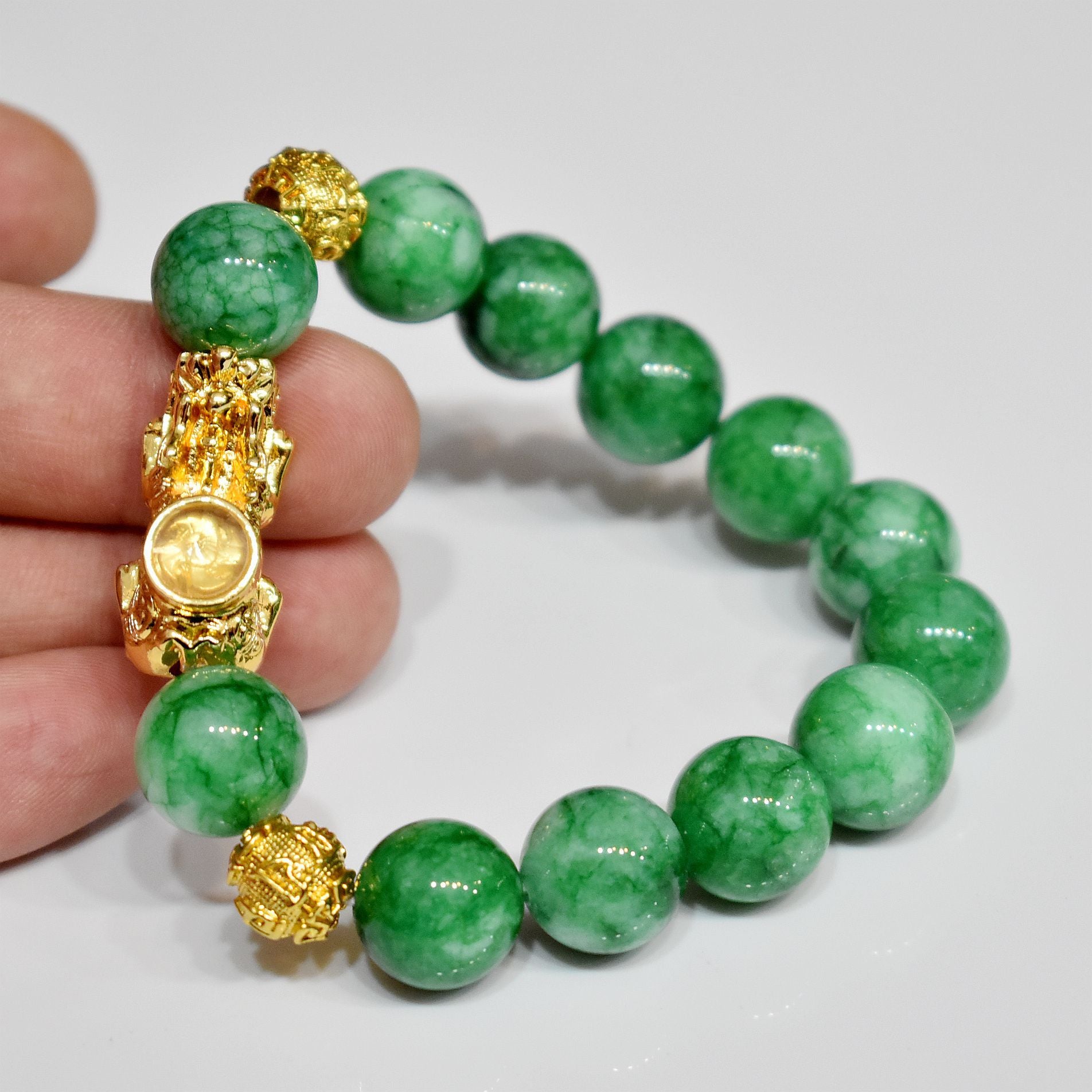 Dark green jade stone bracelet featuring a gold plated Pixiu charm, a symbol for wealth manifestation