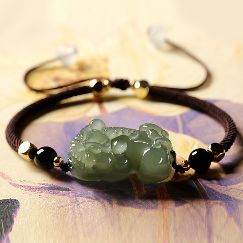 Green jade and black obsidian beaded bracelet featuring a Pixiu charm, a symbolic wealth manifestation accessory.